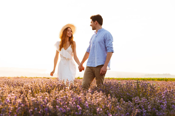 Lovely young couple holding hands at the lavender field - Foto, Bild