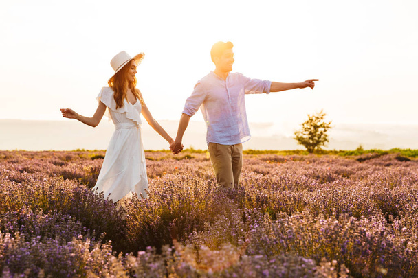 Photo of happy young man and woman dating and walking together outdoor in lavender field - Φωτογραφία, εικόνα