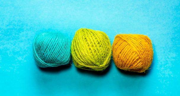 Set of yellowish green, orange and blue hemp threads isolated on blue color background. Colorful Tones, Flat lay. copy space for your text - Фото, зображення