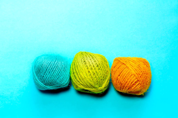 Set of yellowish green, orange and blue hemp threads isolated on blue color background. Colorful Tones, Flat lay. copy space for your text - 写真・画像
