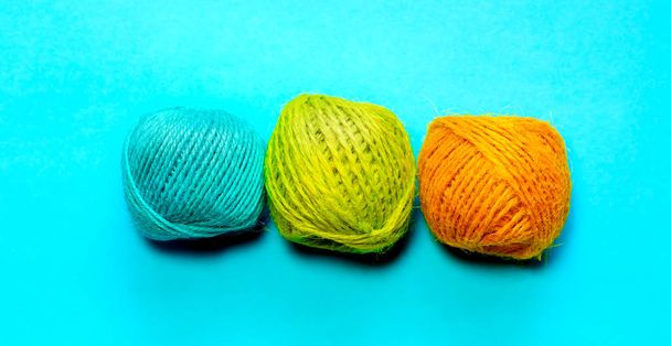 Set of yellowish green, orange and blue hemp threads isolated on blue color background. Colorful Tones, Flat lay. copy space for your text - Fotó, kép