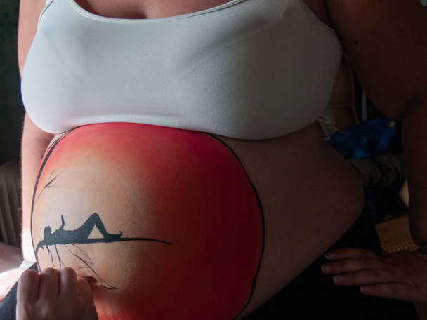Zpěvačkou Malování břicho těhotné mladé ženy s těla barvy a štětce - Fotografie, Obrázek