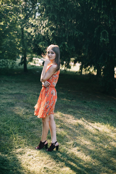Beautiful young girl in a summer red dress in a park - Photo, image