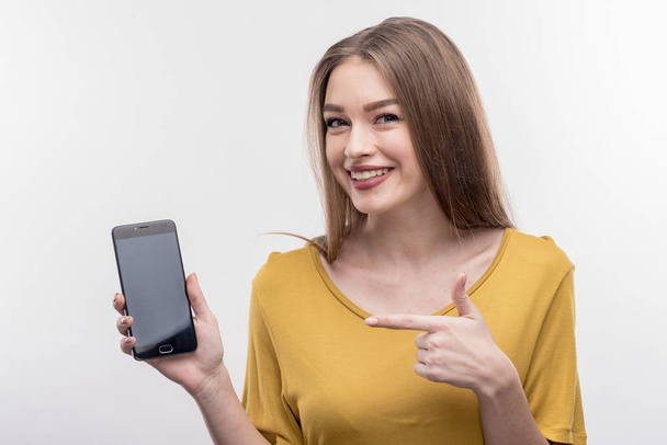 Pleasant positive blonde-haired woman holding her black smart phone - Foto, Bild