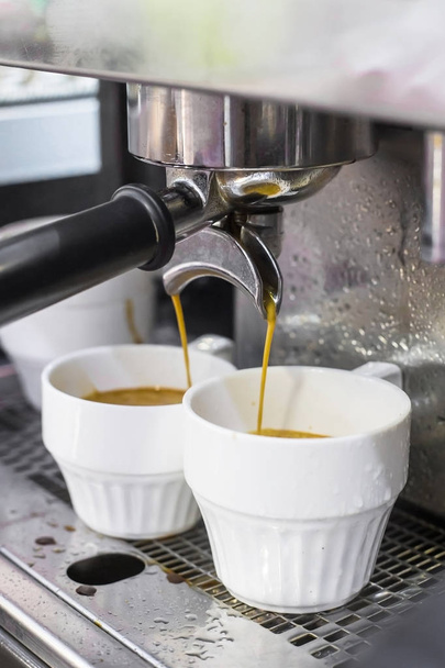 Une machine à café prépare deux expresso dans deux tasses en verre dans un café. Le travail de la machine à café. Culture de la cafetière dans la ville
 - Photo, image