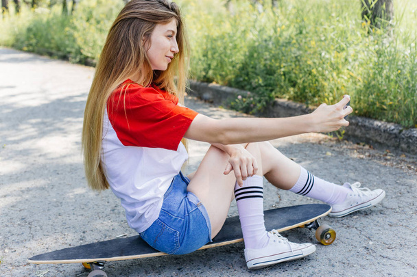 Beautiful skater woman riding on her longboard in the city - Photo, image