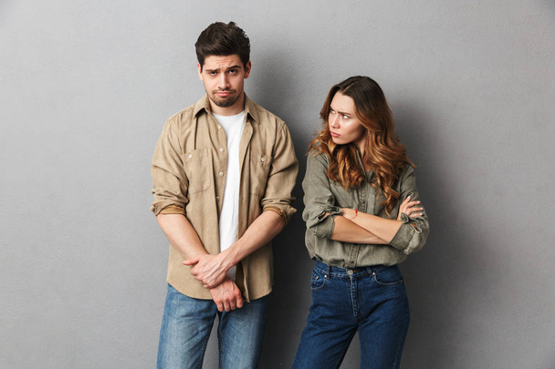 Portrait of an upset young couple having an argument isolated over gray background - Photo, image