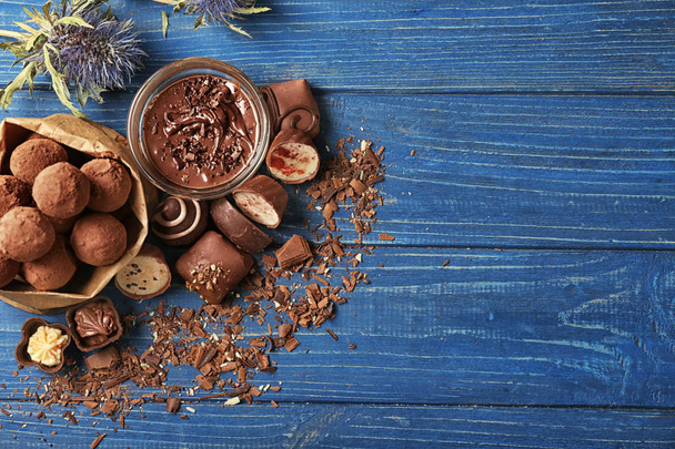 Сумка с вкусными конфетами и миска шоколада, разложенная на деревянном столе
 - Фото, изображение