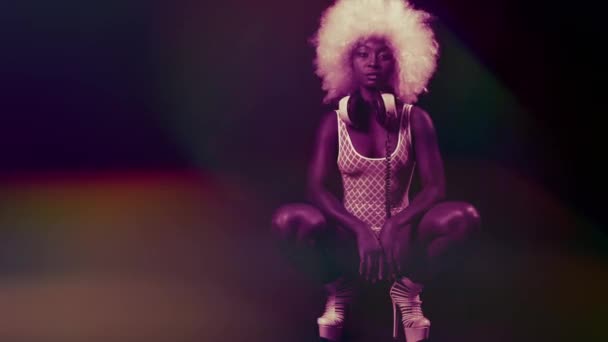 Gyönyörű afrikai nő afro paróka jelentő guggolt fehér fehérnemű és fejhallgató. - Felvétel, videó