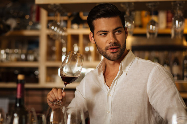 Attractive nice man enjoying to drink wine - Foto, imagen