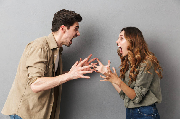 Portrait of an angry young couple having an argument isolated over gray background, shouting - Fotoğraf, Görsel