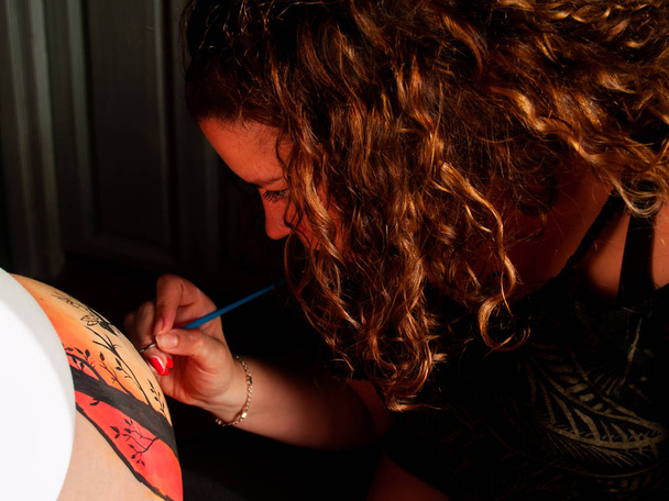 Kadın sanatçı karın hamile bir genç kadının vücut boya ve fırça ile boyama - Fotoğraf, Görsel