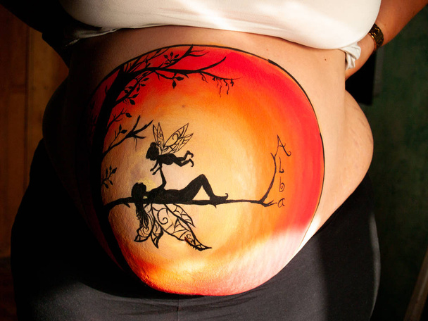 Body art. Painted belly of a pregnant young woman with a fairy drawing - Photo, Image