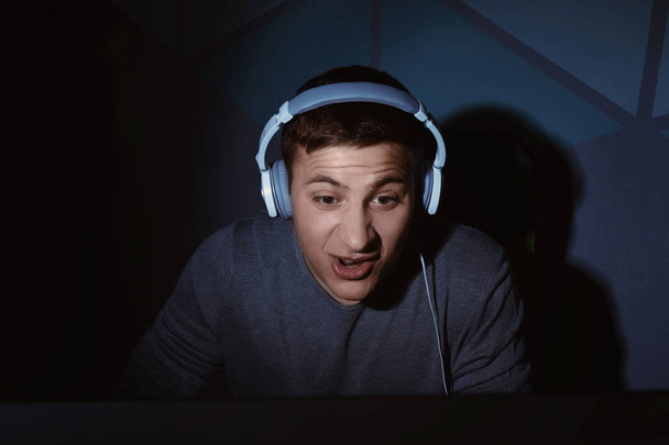 Молодой человек играет в видеоигры дома в темноте
 - Фото, изображение