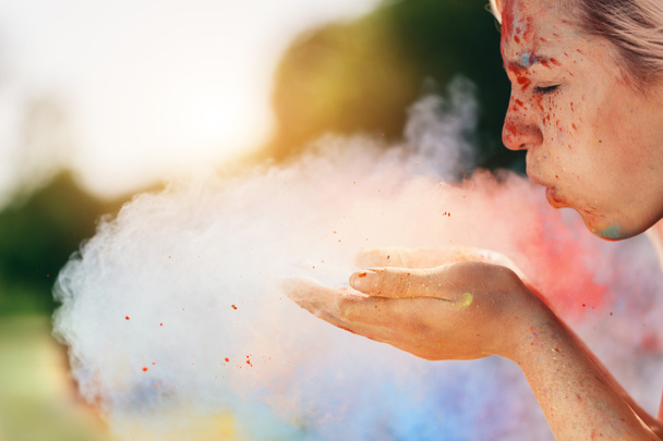 Young woman blowing colorful powder from hand. Holi festival. - Photo, Image
