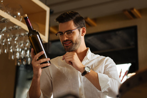 Joyful bom homem estudando a garrafa de vinho
 - Foto, Imagem