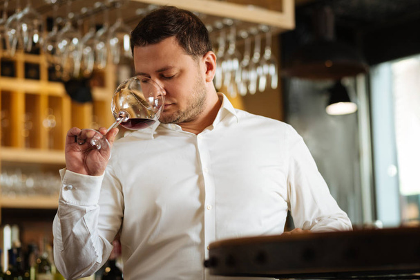 Nice good looking man holding a glass with red wine - Zdjęcie, obraz