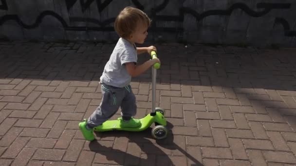 Dziecko jazda konna zielony hulajnoga - Materiał filmowy, wideo