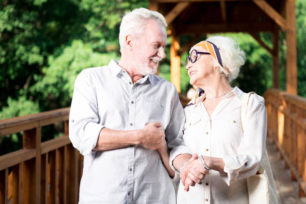 Elderly bearded man smiling while holding hand of his wife - Photo, image