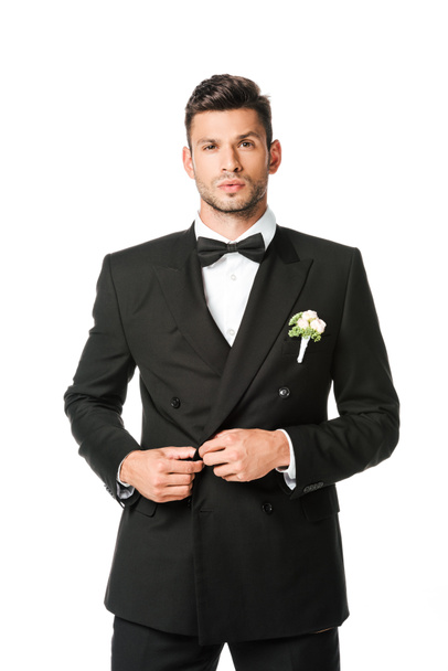 handsome groom buttoning suit and looking at camera isolated on white - Photo, Image