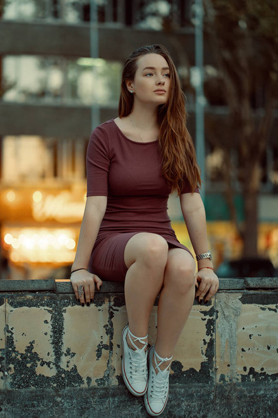 Kaunis yksinäinen tyttö haaveilee ja ajattelu, turisti nuori nainen poseeraa kaupungin kadulla rakennusten ja valot taustalla
. - Valokuva, kuva