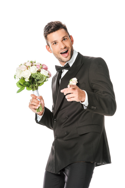 happy young groom with bridal bouquet pointing at camera isolated on white - Φωτογραφία, εικόνα
