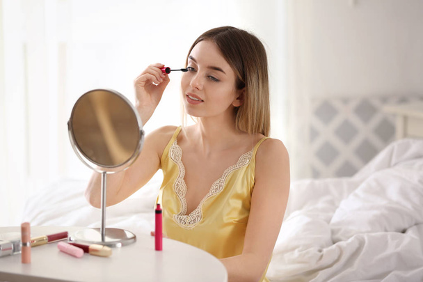 Beautiful young woman applying makeup in morning - Photo, Image