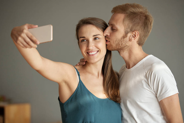 Gelukkige vrouw foto praten wanneer haar vriendje haar op de wang kussen - Foto, afbeelding