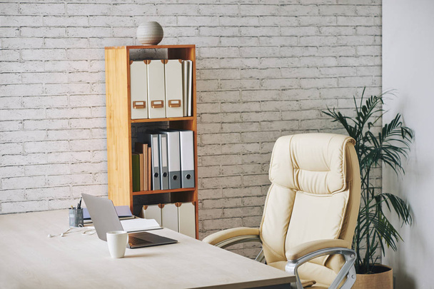 Изображение рабочего места с ноутбуком на столе в современном офисе
 - Фото, изображение