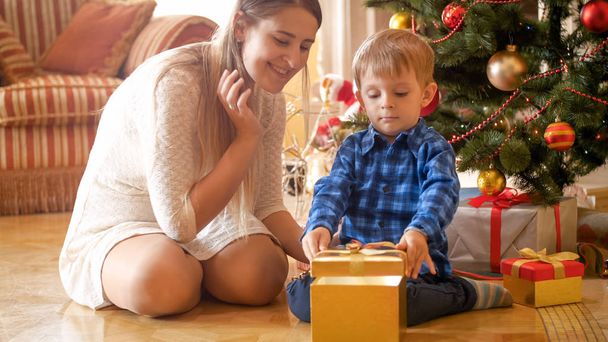 Heureux jeune mère et tout-petit fils sont excités de cadeaux de Noël
 - Photo, image