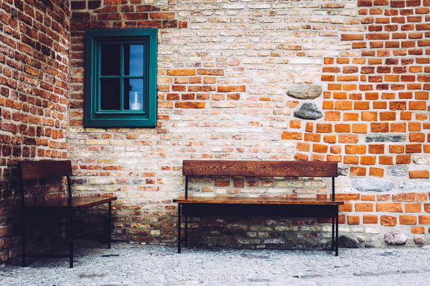 Dwa drewniane ławki stojąc przed starego budynku z oknem zielony z cegły. Stare Miasto, Gdańsk, Polska. - Zdjęcie, obraz