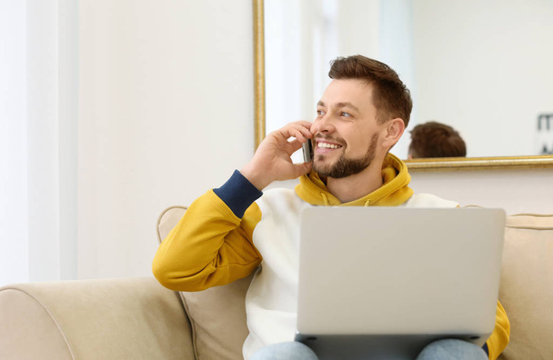 Freelancer puhuu puhelimessa, kun käytät kannettavaa tietokonetta kotona
 - Valokuva, kuva