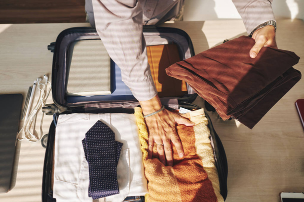 Gros plan de l'homme d'affaires emballant des vêtements dans un sac de voyage
 - Photo, image