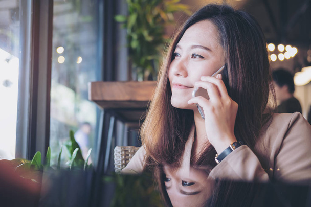 Piękna dziewczyna azjatyckich rozmawia inteligentny telefon z uśmiechniętą buźką w restauracji - Zdjęcie, obraz