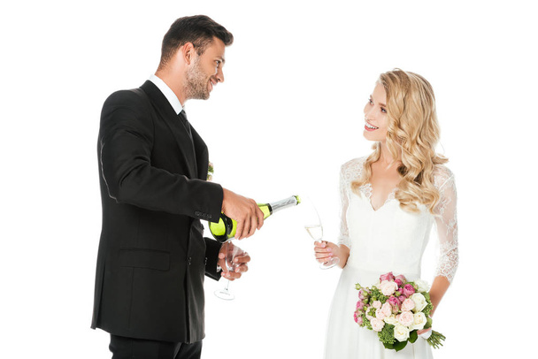vőlegény szakadó pezsgő, míg a menyasszony kezében elszigetelt fehér üveg - Fotó, kép