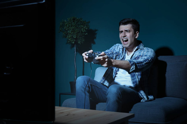 Young man playing video game at home in the evening - Photo, Image