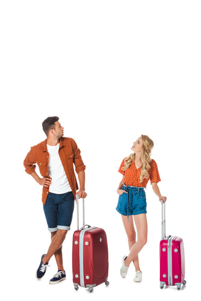 pareja joven con el equipaje mirando hacia arriba aislado en blanco
 - Foto, Imagen