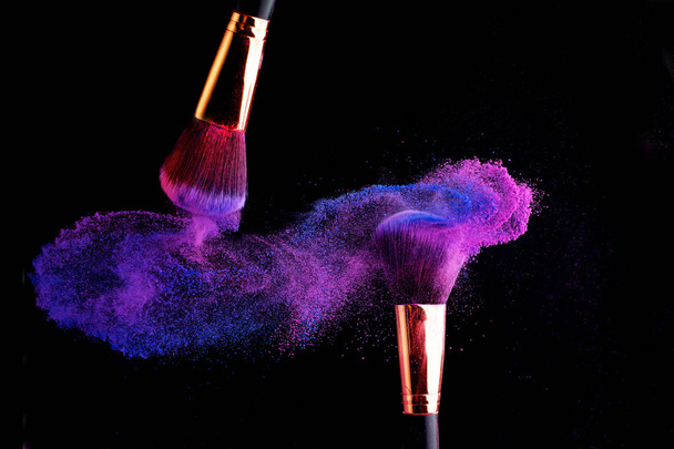 Make-up brush with colorful powder splashes explosion on black background - Photo, Image