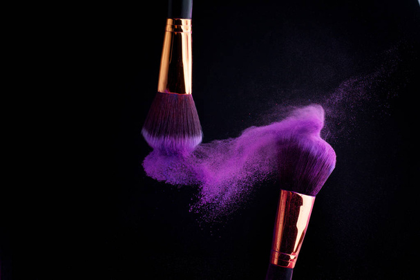 Make-up Pinsel mit bunten Puderspritzern Explosion auf schwarzem Hintergrund - Foto, Bild