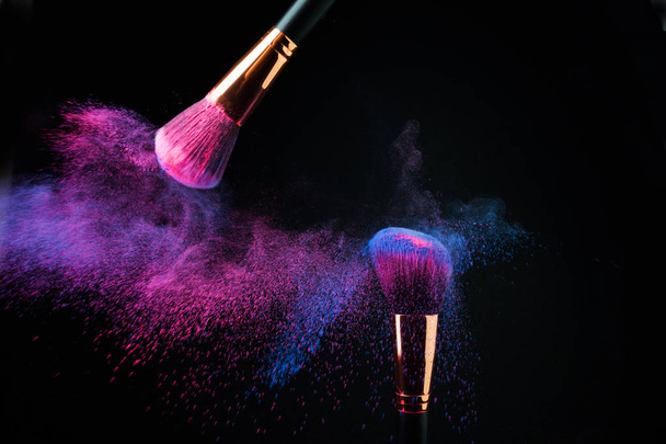 Make-up brush with colorful powder splashes explosion on black - Fotó, kép