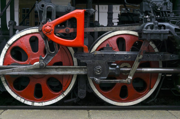 fragment de locomotive à vapeur vintage fonctionnant debout à la gare, gros plan, roues motrices visibles avec un système de pistons, bielles et levier
 - Photo, image
