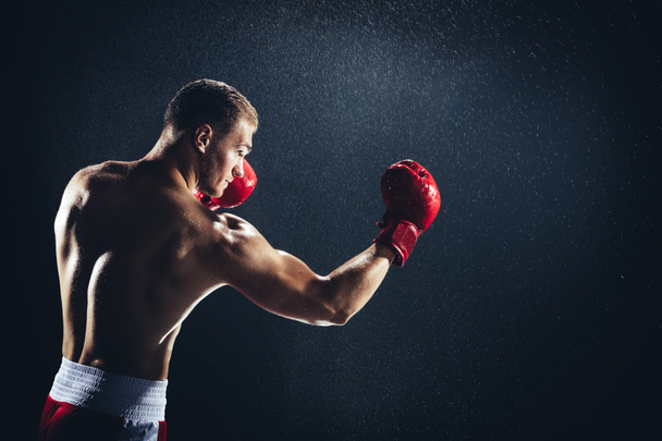 Homme boxe avec des gants rouges sous la pluie. Combattant professionnel, boxeur
. - Photo, image