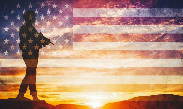 Armed soldier with rifle standing and looking on horizon. USA flag. Silhouette at sunset. War, army, military, guard. - Photo, Image