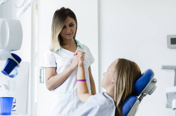 Portrait of little girl how high five to her female dentist. - Foto, Bild