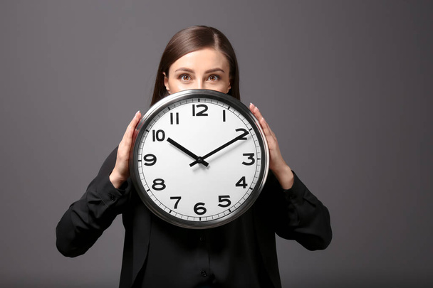 Woman with clock on grey background. Time management concept - Zdjęcie, obraz