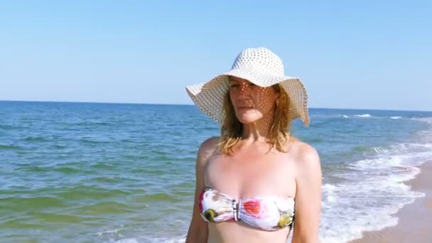 4K. Mujer en traje de baño y sombrero, caminando en la playa del mar. Disparo constante
 - Metraje, vídeo