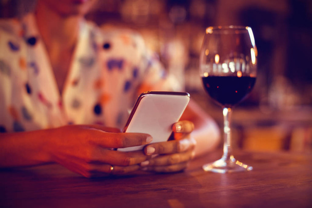 Mid-section of woman using mobile phone in pub - Photo, Image