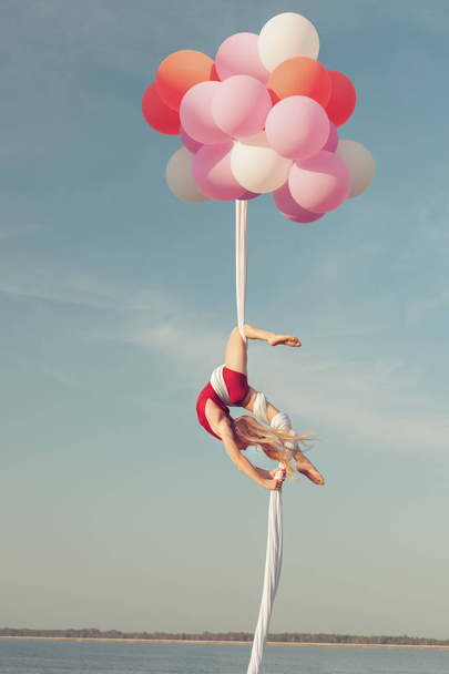Дівчина робить акробатичні трюки. Вона плаває в повітрі на повітряних кулях
. - Фото, зображення