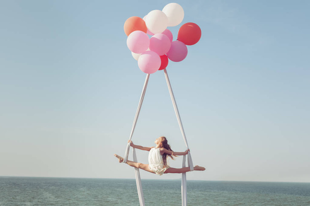 A rapariga faz um fio na tela sobre o mar. Balões manter a tela no ar
. - Foto, Imagem