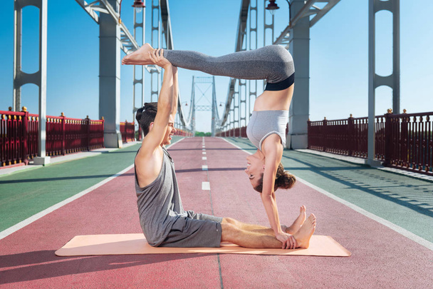 Serious man and woman attempting couple yoga - Foto, imagen